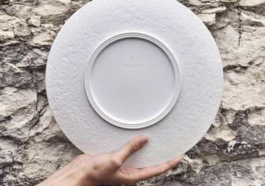 Porcelain plate held up against rock wall .